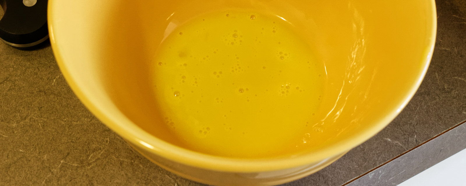 Beaten egg yolk in a yellow bowl